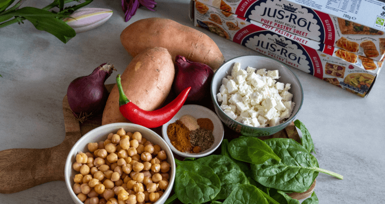 chickpeas, feta cheese, sweet potatoes, chili, onion & spinach leaves put together on wooden plate