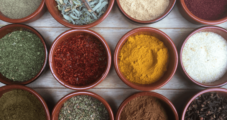 assorted bowls filled with vibrant spices like turmeric, chili powder, cloves etc.