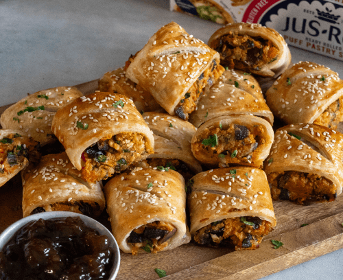 Spinach, Sweet Potato & Feta Sausage Rolls served on a wooden plate with jam