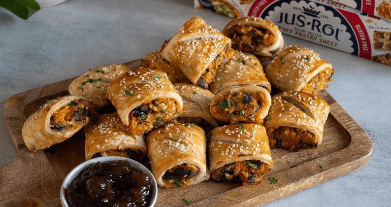 Spinach, Sweet Potato & Feta Sausage Rolls served on a wooden plate with jam